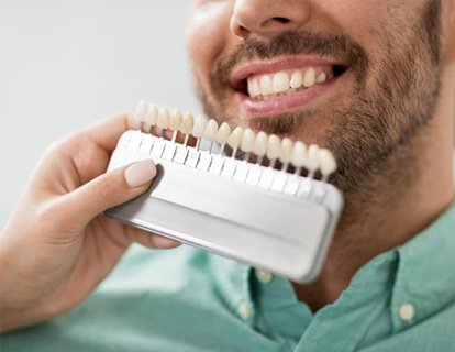 Dentist comparing dental veneers to a patient’s smile