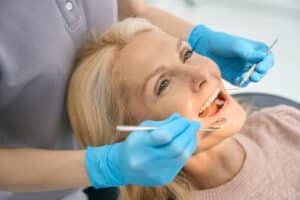 Woman in dental chair being examined by dentist to see if she’s a dental crown candidate