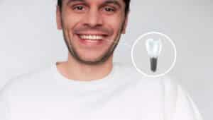 Man smiling with a close up of a dental implant to show that he received one after dental bone regeneration.